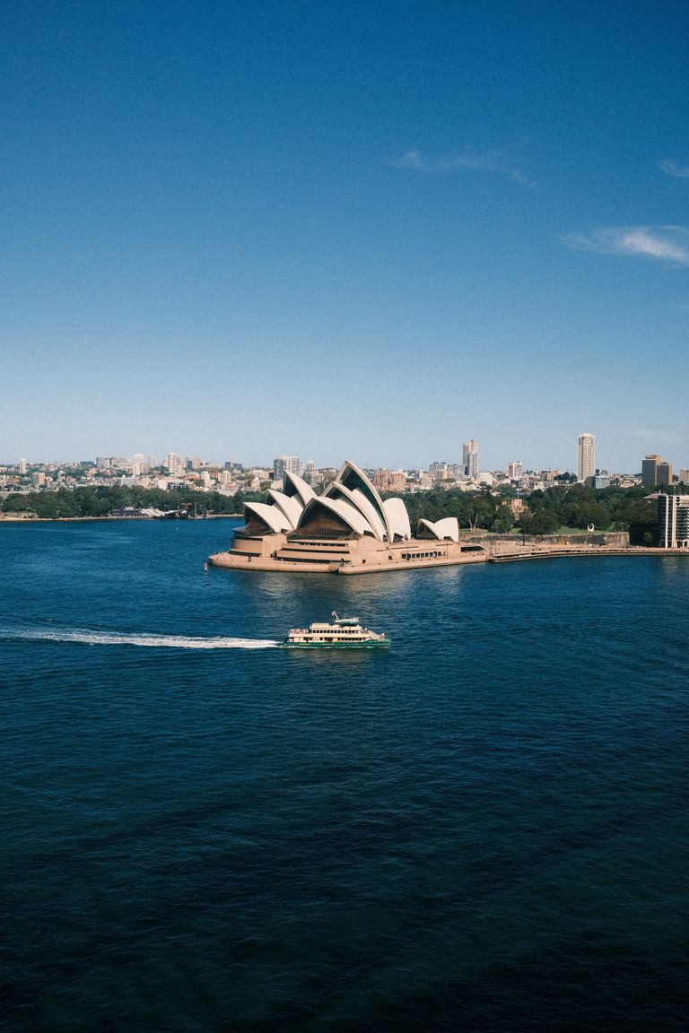A scenic aerial view of the iconic Sydney Opera House and harbor ferry.