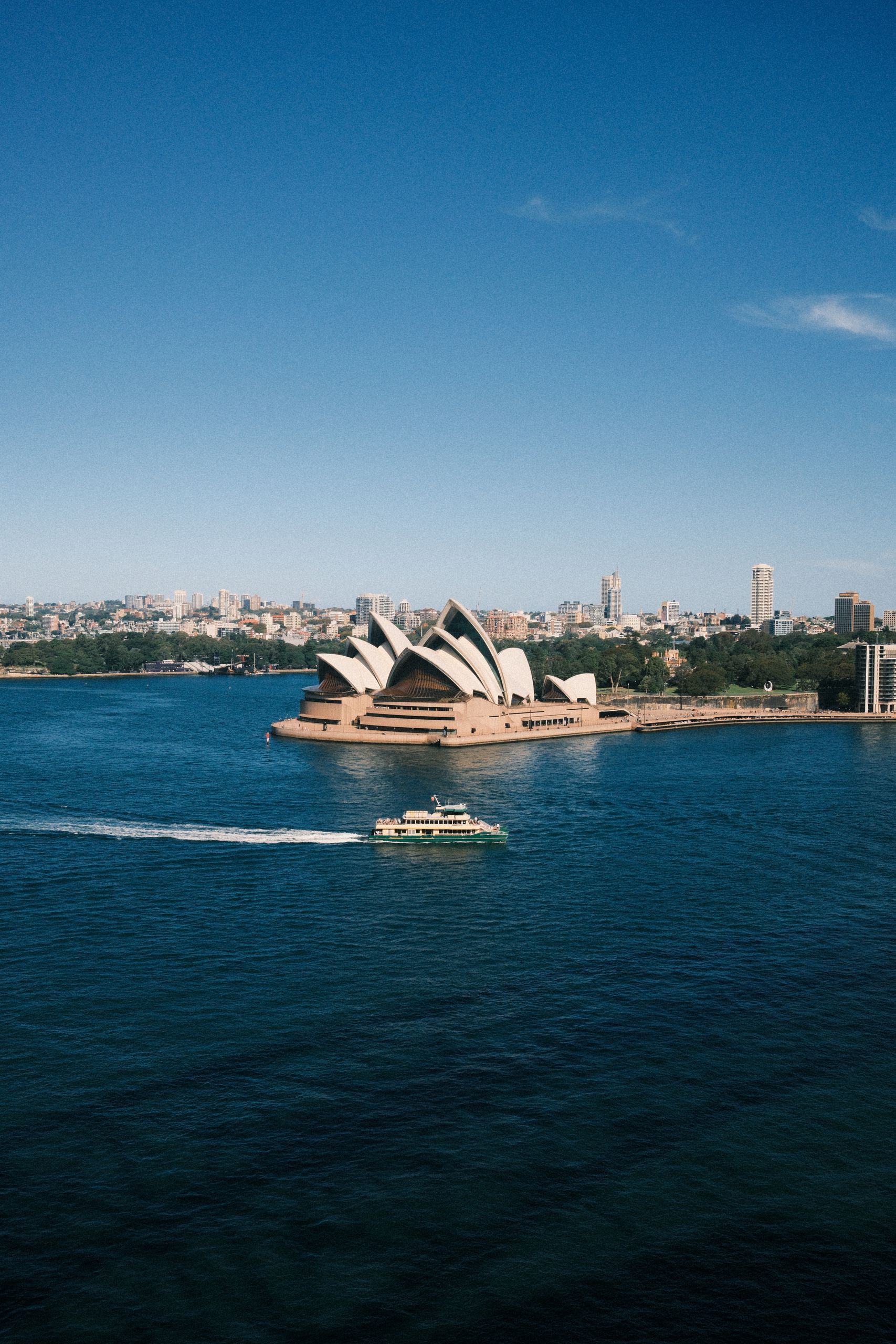 A scenic aerial view of the iconic Sydney Opera House and harbor ferry.