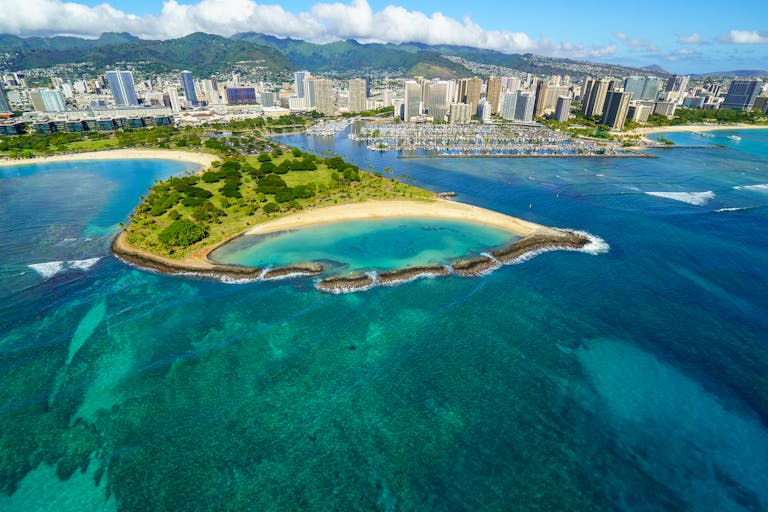 Stunning aerial view of Honolulu's coastline with beaches, skyscrapers, and turquoise waters.